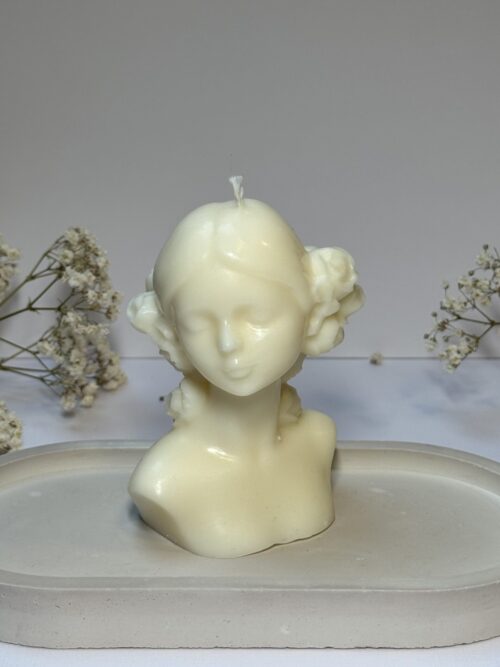 Świeca sojowa w kształcie kobiety z wiankiem na podstawce gipsowej, w tle gipsówka