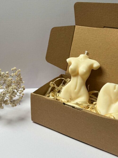 Świece sojowe w kształcieciała kobiety i pośladków, zapakowane w pudełko prezentowe, w tle gipsówka