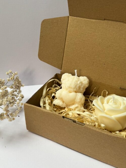Świece sojowe w kształcie misia i róży, zapakowane w pudełko prezentowe, w tle gipsówka